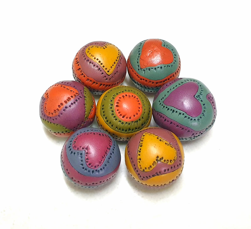 Hollow round polymer clay beads made by comprising pieces of clay in various colors and patterns together.